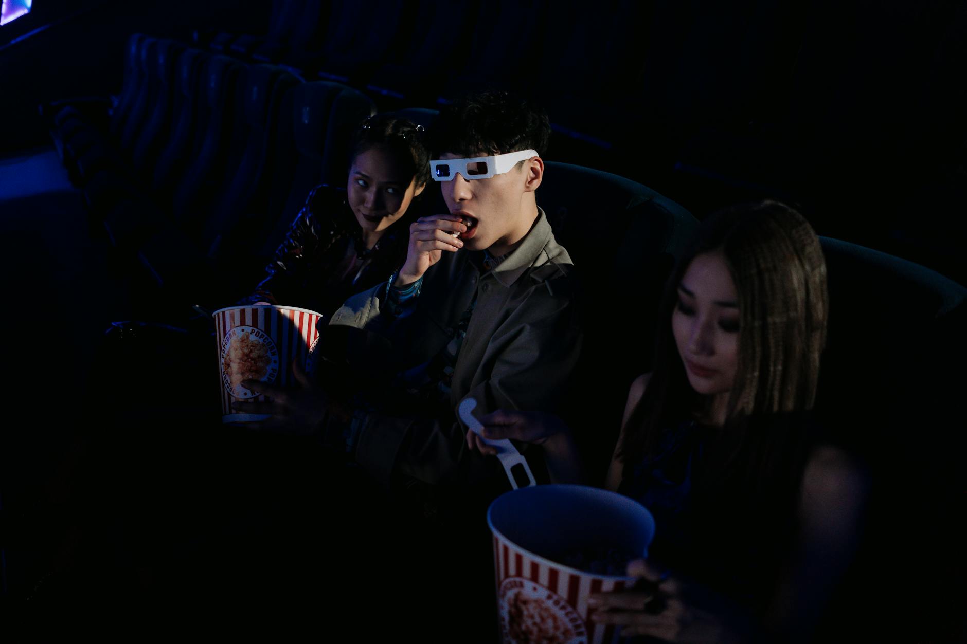 Young friends in cinema seats with popcorn