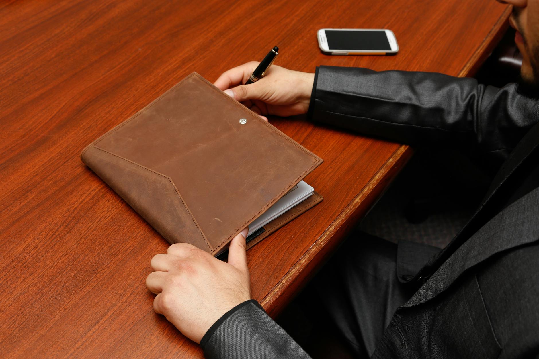 Executive at a polished wood desk with a leather portfolio