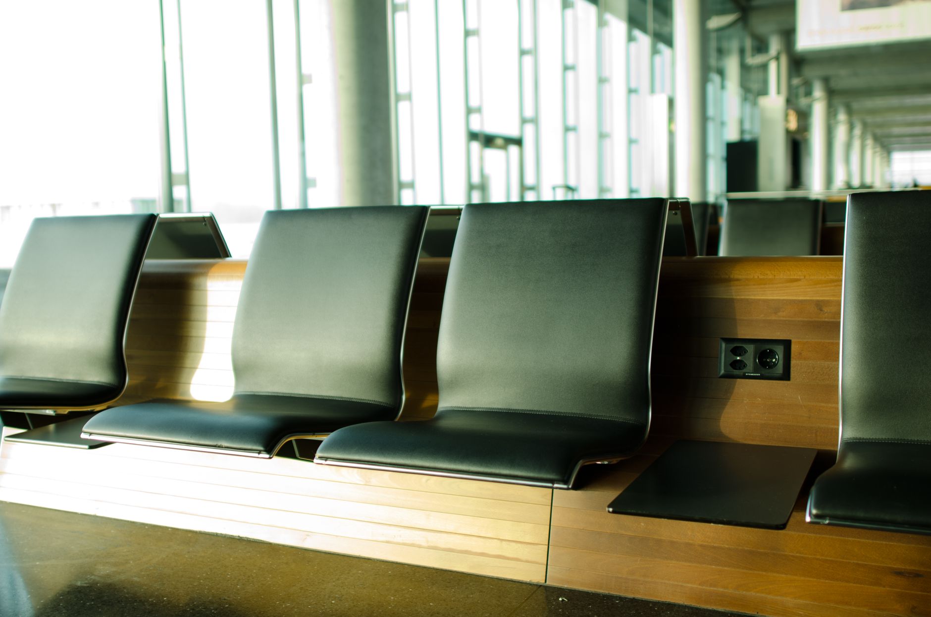 Empty seats at an airport departure gate beside a large window